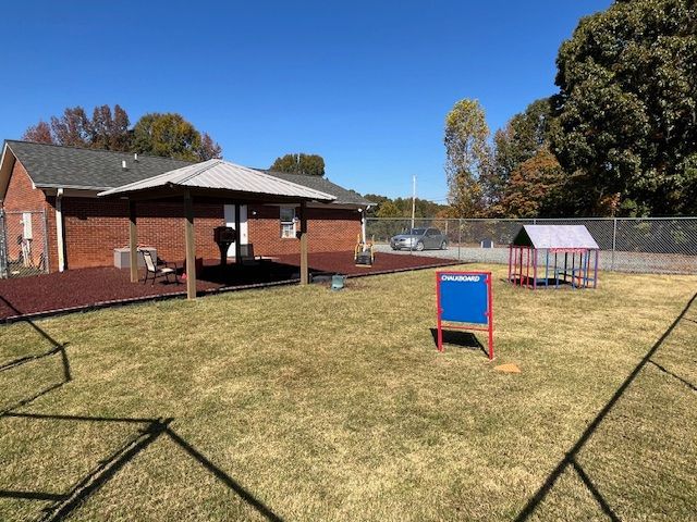 A fenced in yard with a brick house in the background