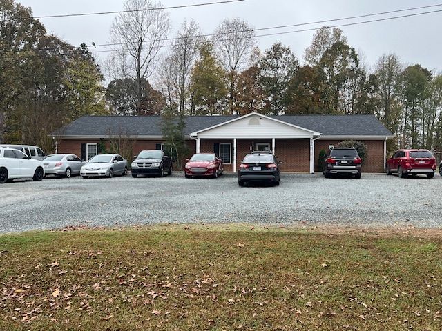 A row of cars are parked in front of a house.