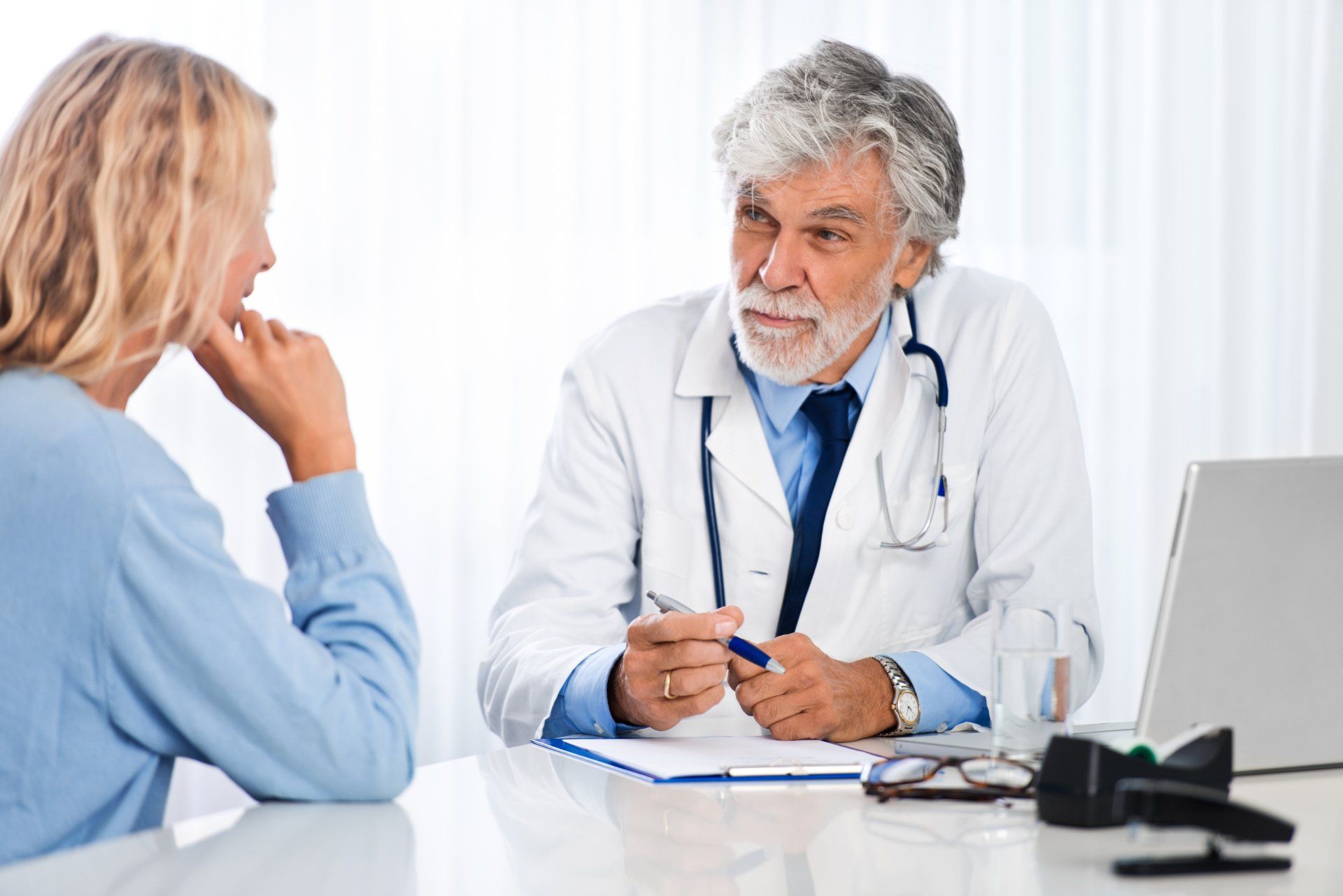 A doctor is talking to a patient in front of a laptop computer.