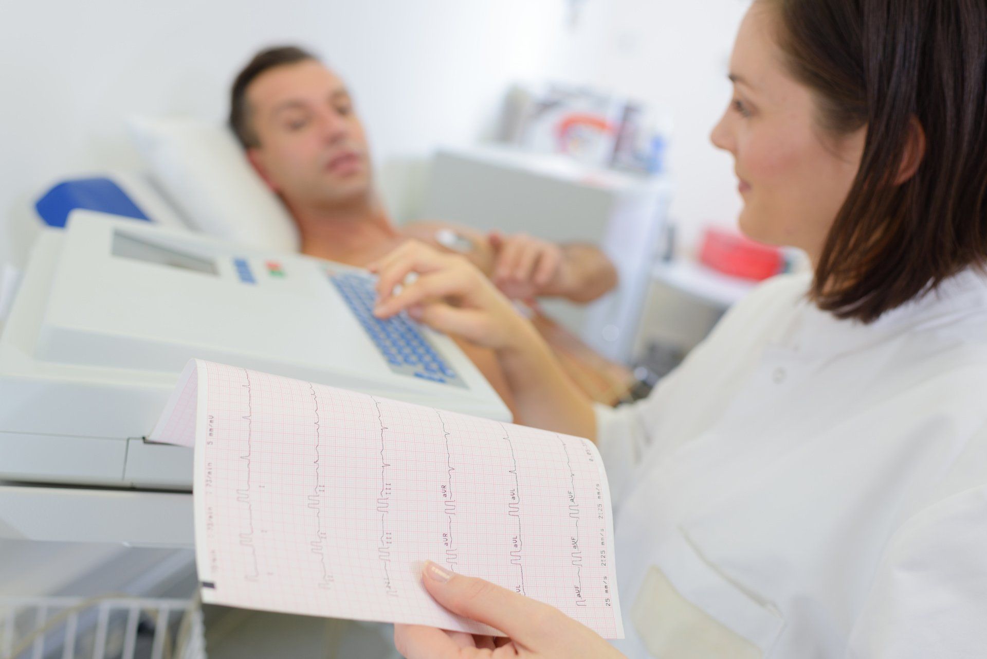 A woman is holding a piece of paper in front of a man in a hospital bed.
