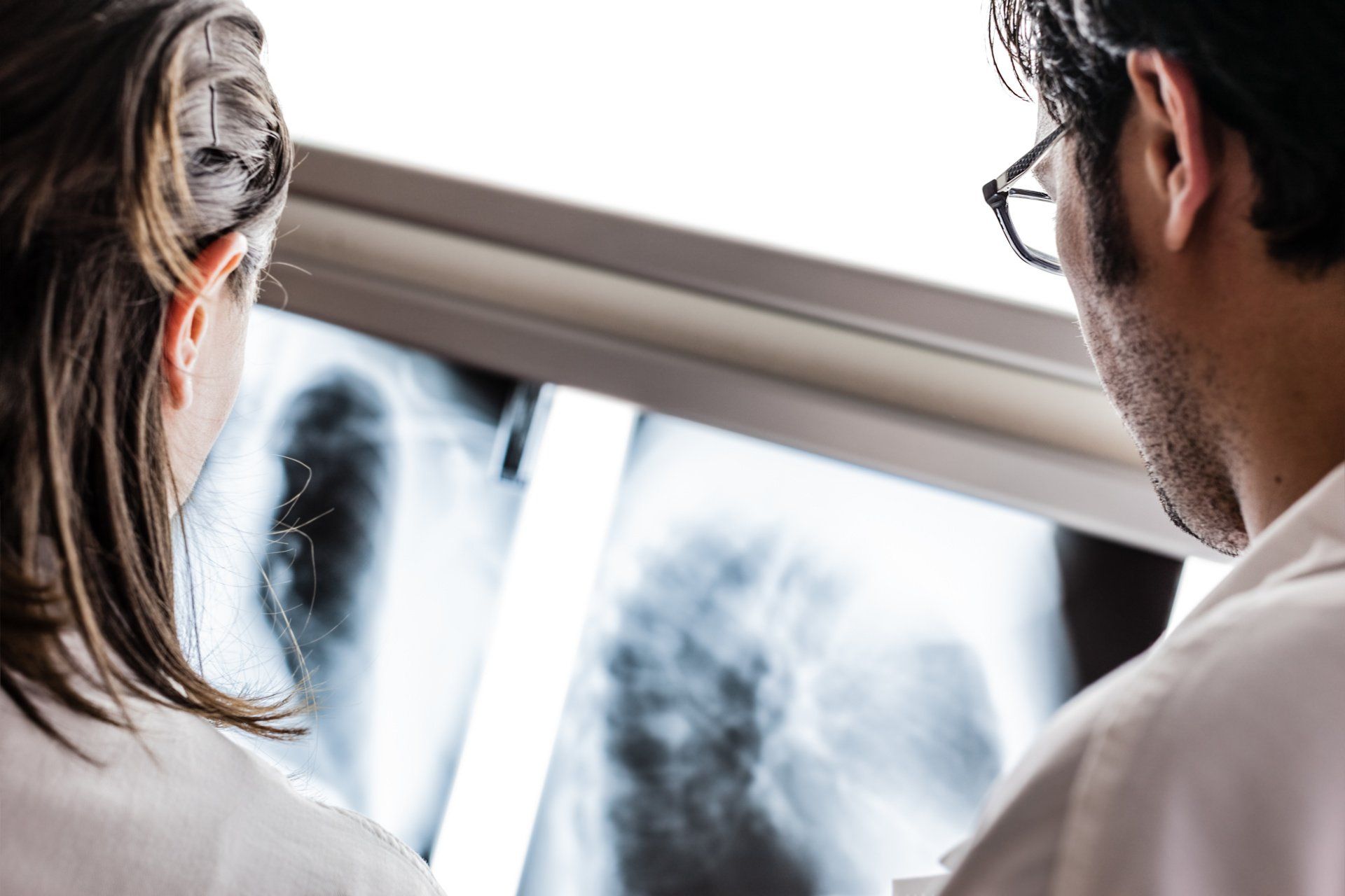 A man and a woman are looking at an x-ray of a person 's lungs.