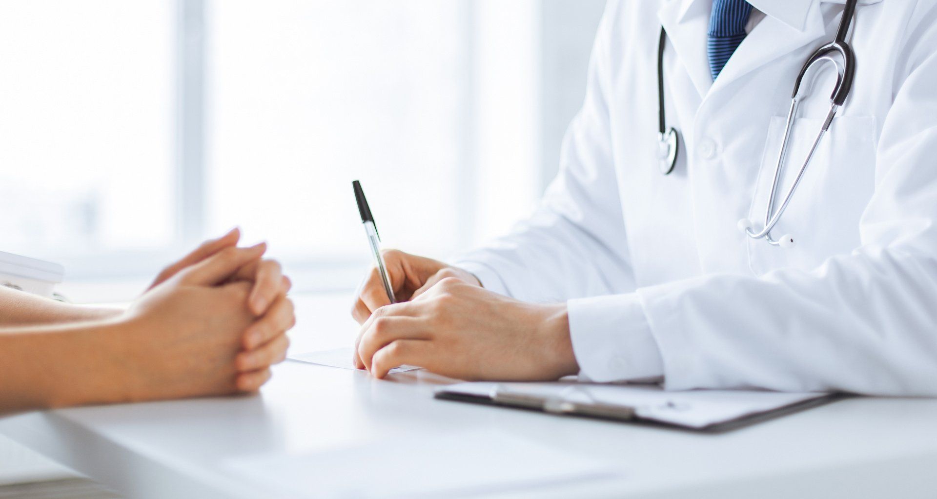 A doctor is sitting at a table talking to a patient.