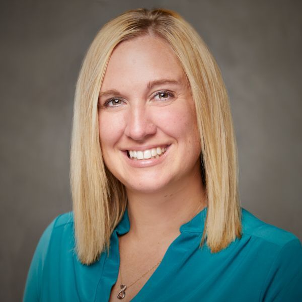 A woman in a blue shirt is smiling for the camera.