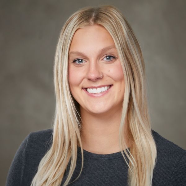 A woman with blonde hair and blue eyes is smiling for the camera.