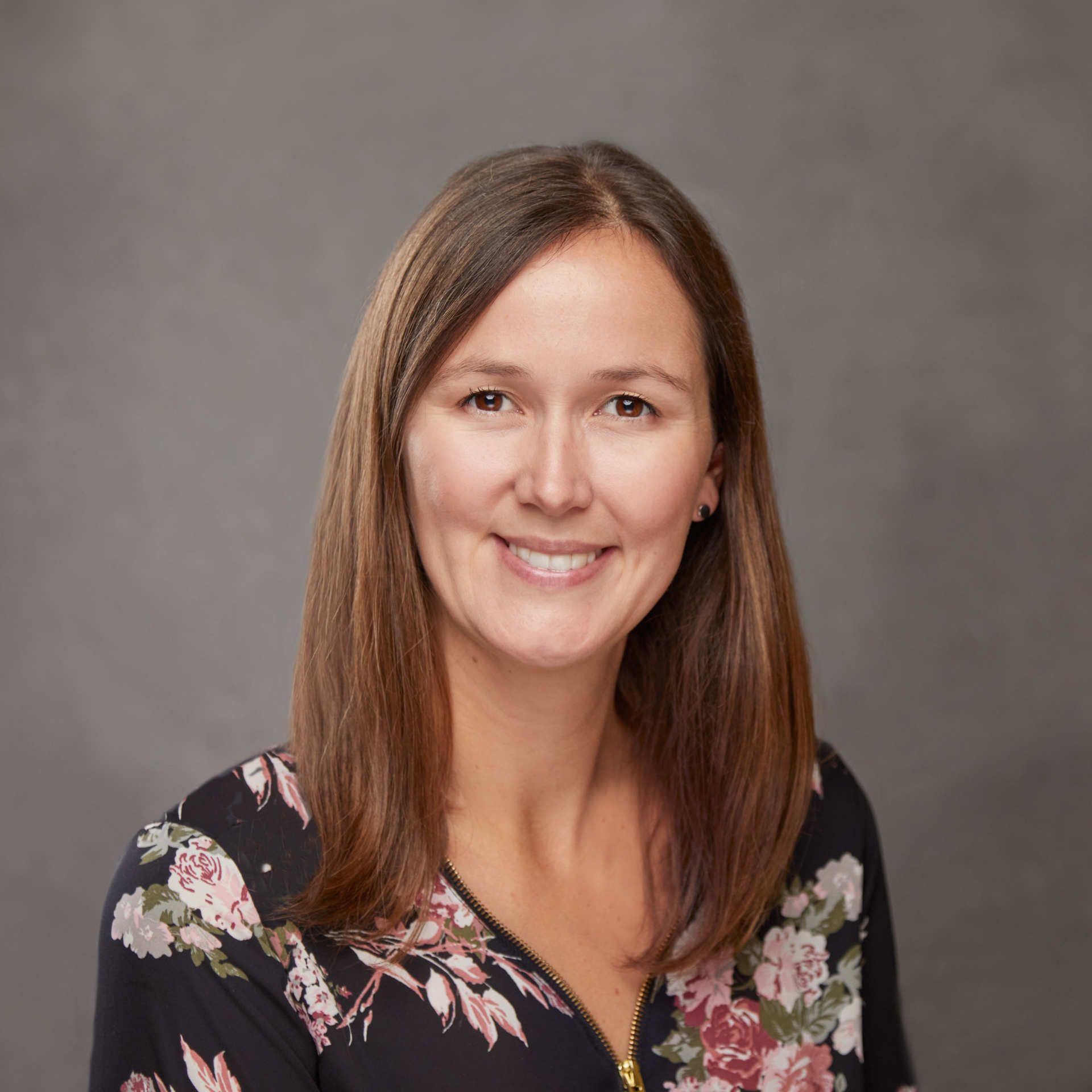 A woman in a floral shirt is smiling for the camera.