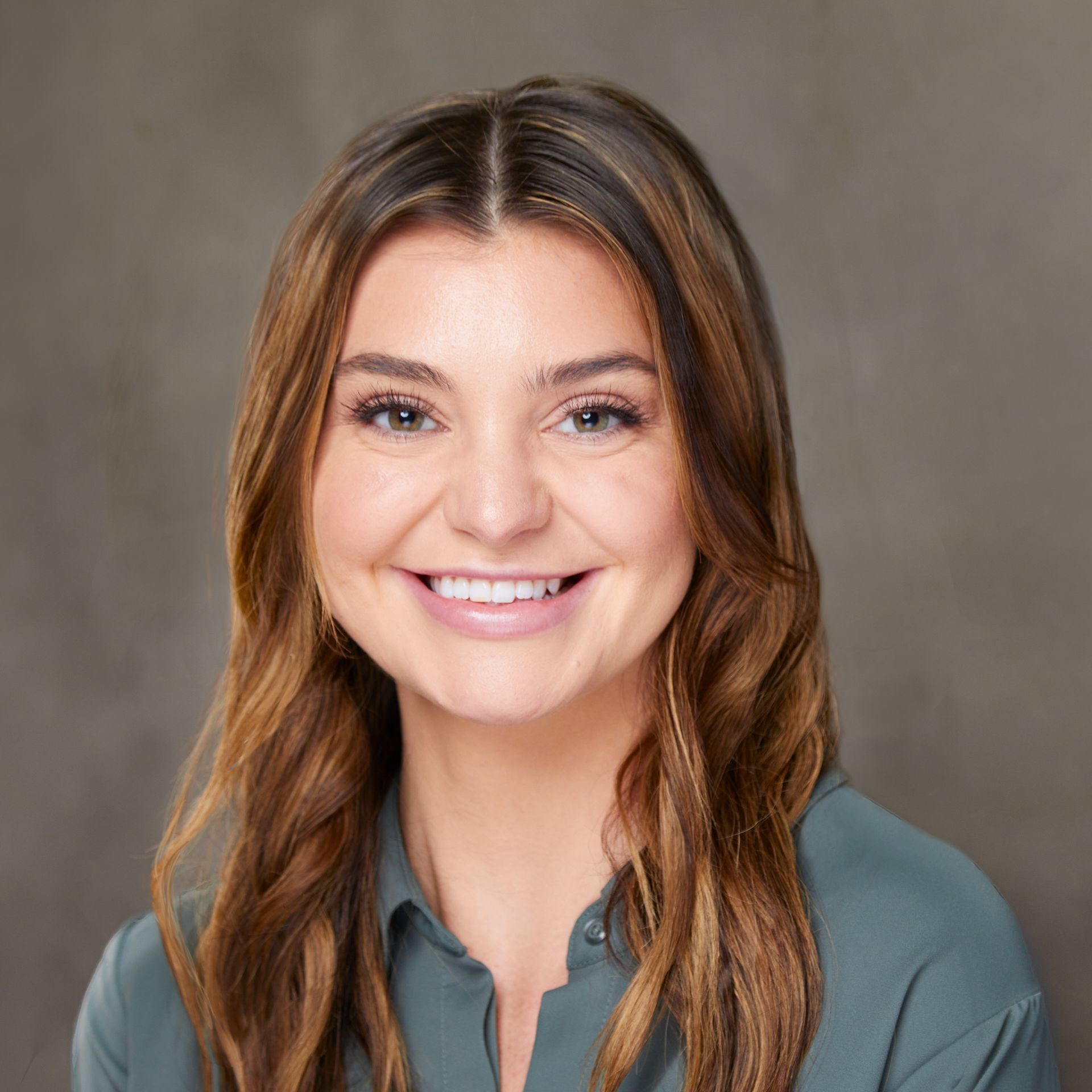 The woman is smiling for the camera and wearing a green shirt.