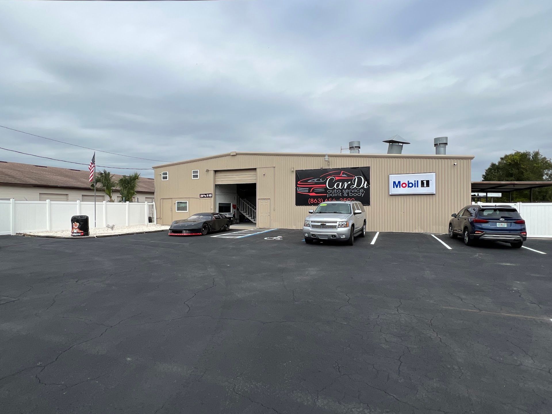 Car repair shop with a black asphalt parking lot and cars. | CarDi Automotive