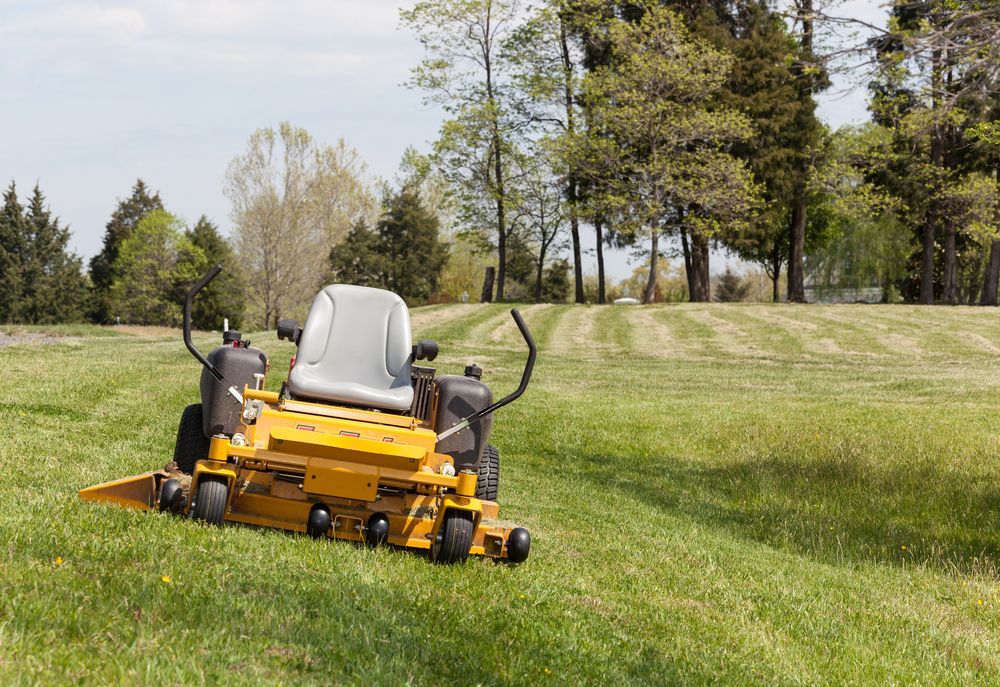Yellow Riding Lawn Mower On A Grassy Hill, Cutting Grass — Stihl Shop Atherton In Atherton, QLD