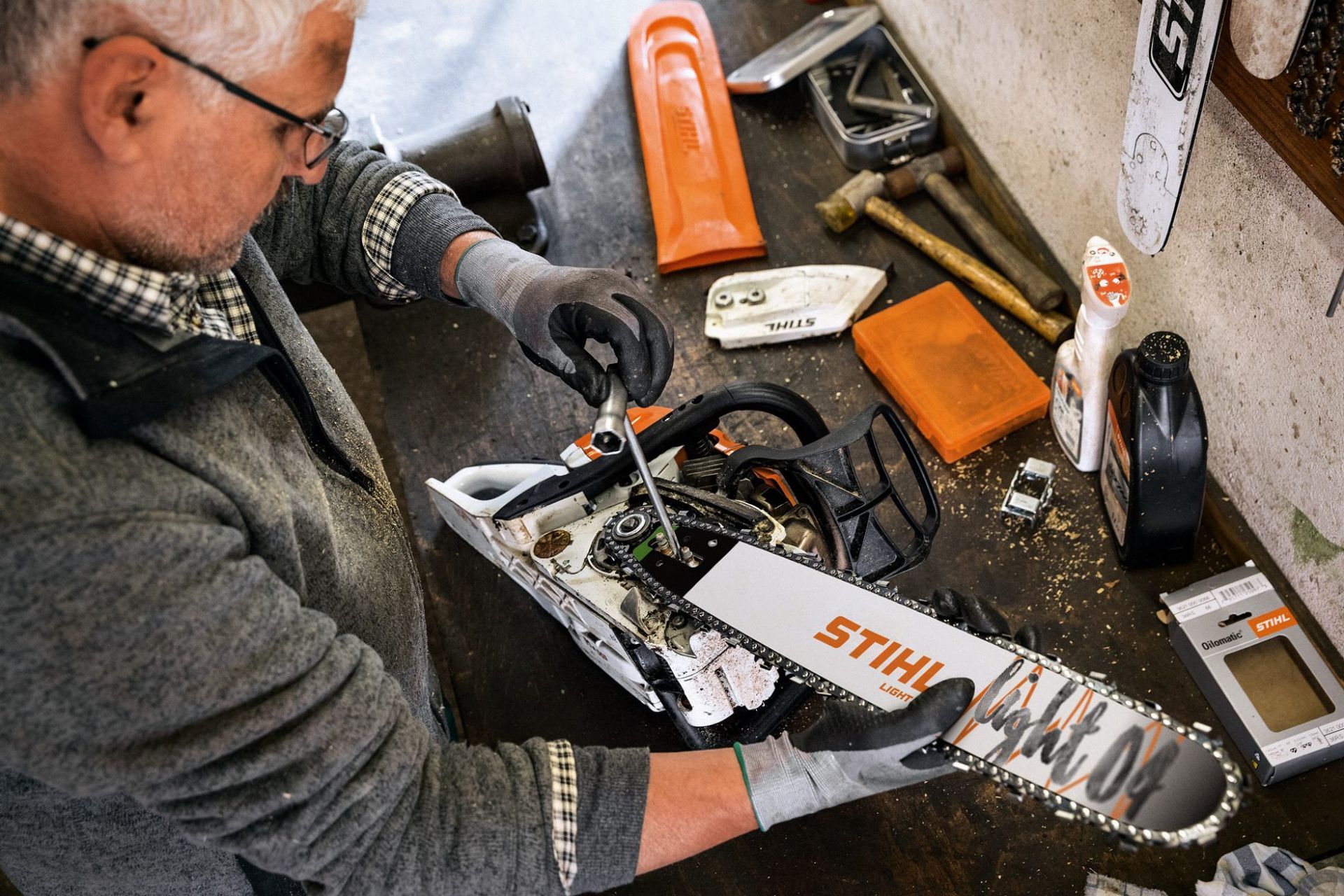 Person repairing a STIHL chainsaw on a workbench, with tools and parts scattered around  — Stihl Shop Atherton In Atherton, QLD
