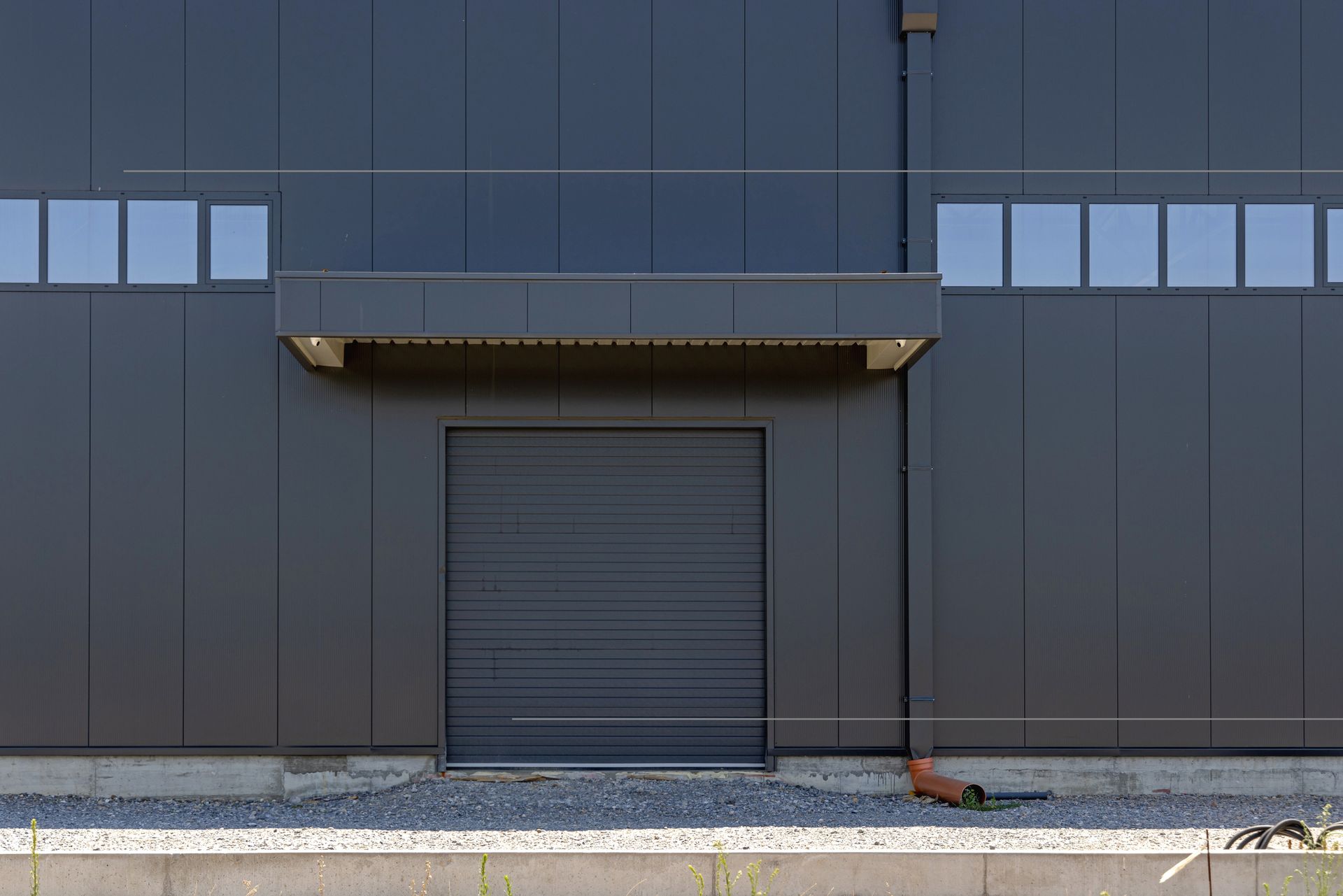 A closed loading overhead door at a new distribution warehouse building completely painted black. A closed loading overhead door at a new distribution warehouse building completely painted black.