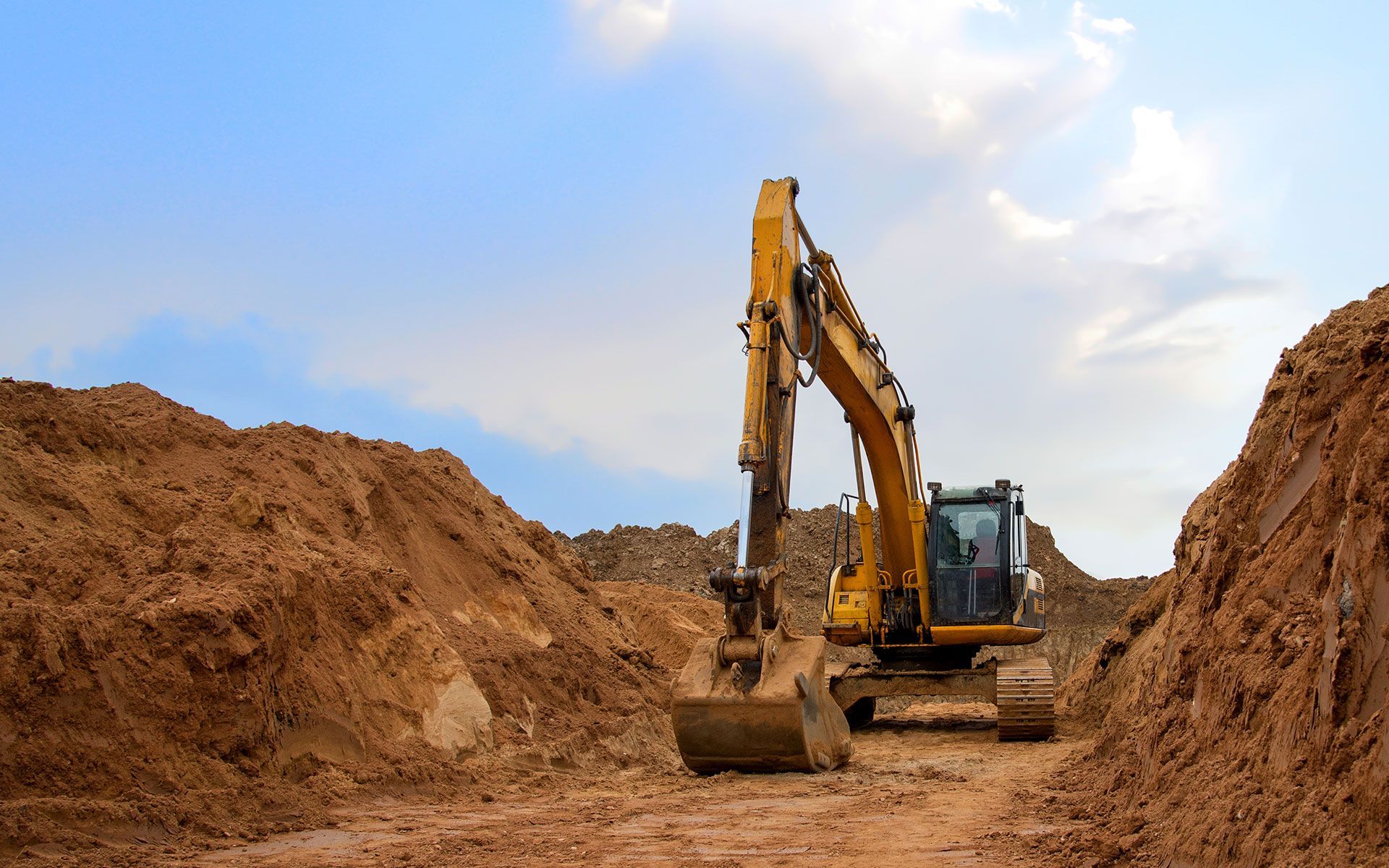 A yellow excavator is digging a hole in the dirt.