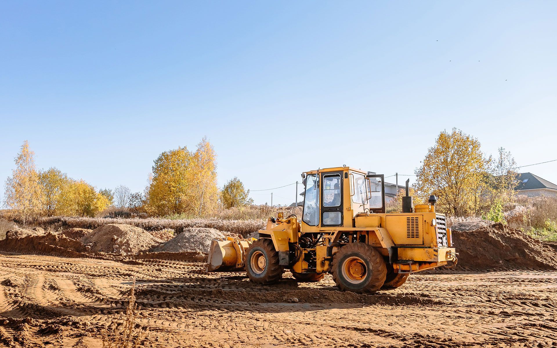 A yellow bulldozer is sitting on top of a dirt field.