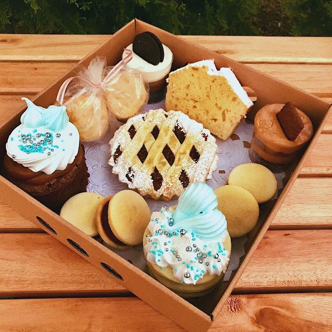 Caja de postre con cupcakes, galletas, tarta y pastel sobre una superficie de madera.