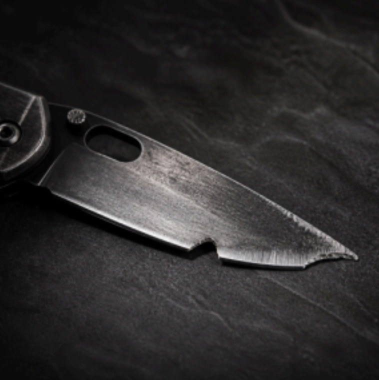 Close-up of a silver knife blade on a dark textured surface