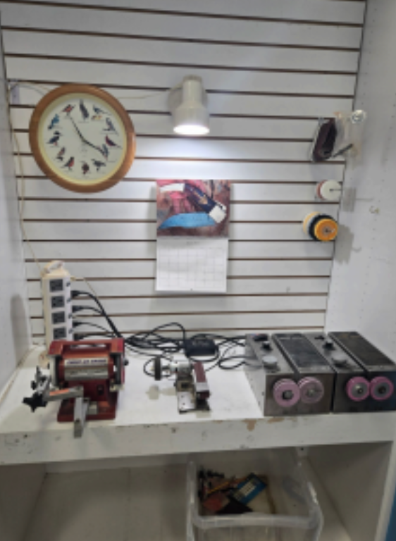 Wall-mounted workbench with clock, lamp, tools, and small machinery in a workshop display