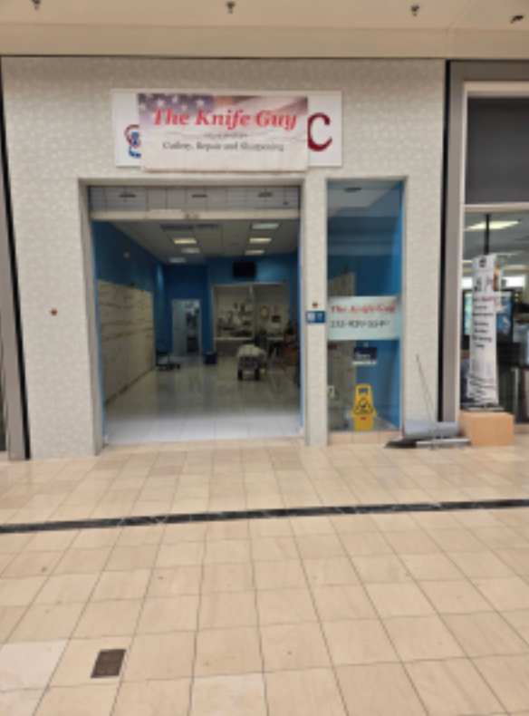 Storefront entrance to “The Knife Guy” in a mall corridor, with blue interior and a large red “C” sign.