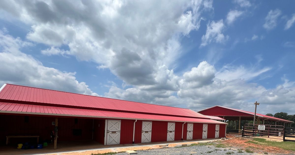Red barn with white doors under a cloudy blue sky.