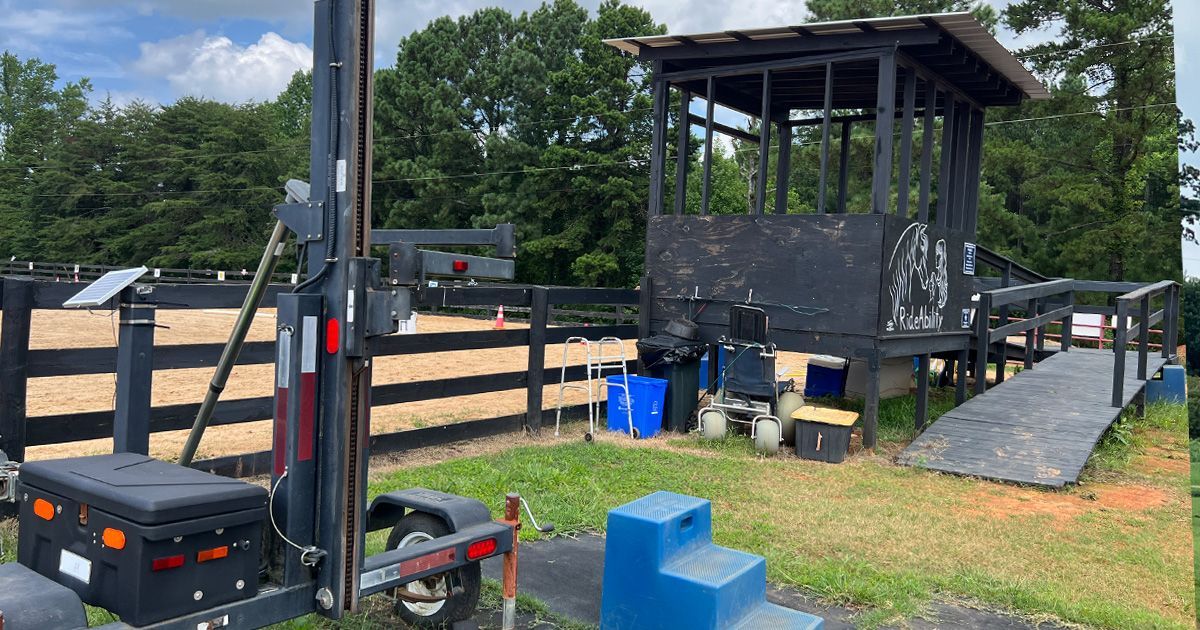 Outdoor training course with wooden structures; a black and tan pen, blue blocks, and a ramp.