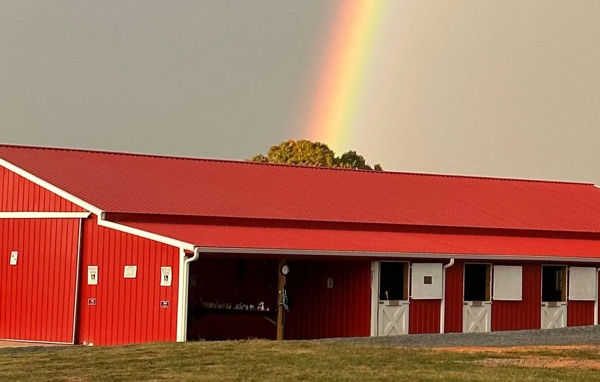 Red barn with rainbow arching overhead.