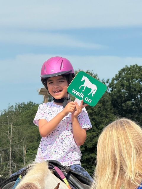 Young girl on a horse holds 