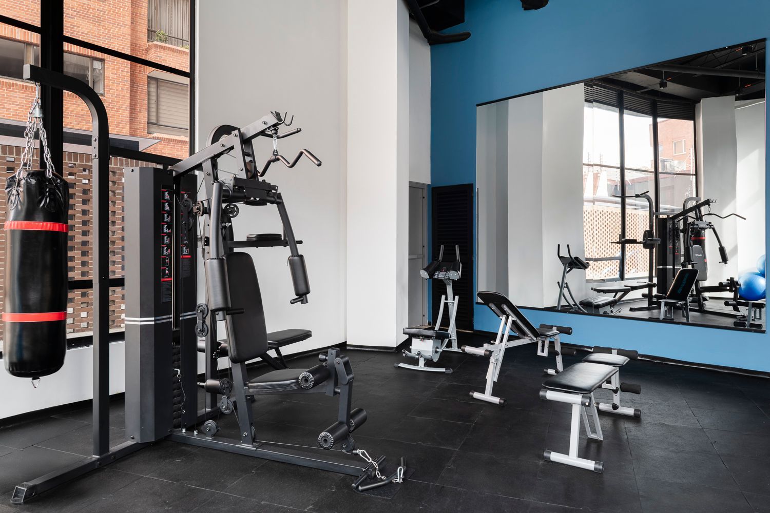 Gimnasio interior con máquinas de ejercicio y zona de entrenamiento en hotel en Bogotá.