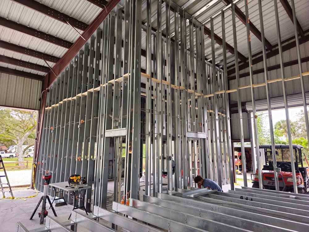 Construction of a metal-framed structure inside a metal building, with a person working.
