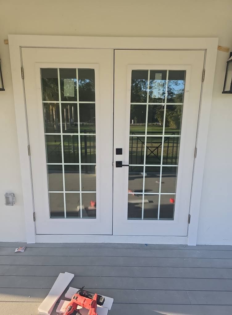 White French doors with multiple panes, black hardware, and light-colored trim. Outdoors.