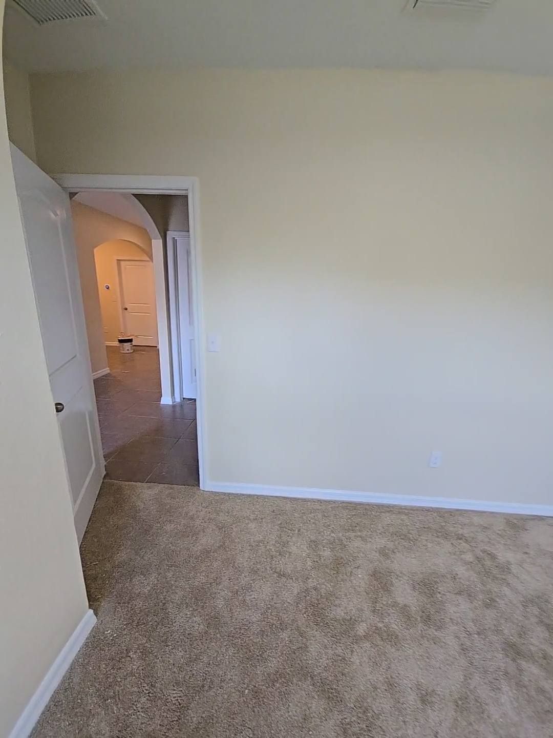 Beige-walled room with doorway leading to hallway and carpeted floor.