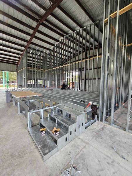 Metal frame construction of a building interior. Stairs, walls, and a sloped roof visible.
