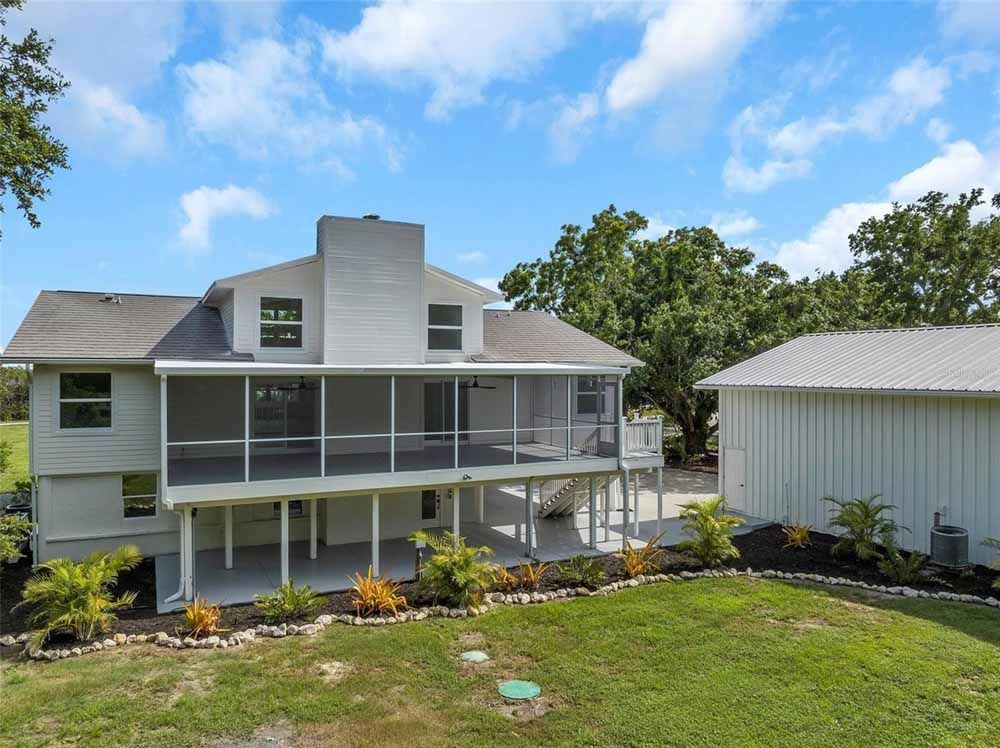 Two-story white house with screened porch, chimney, and detached white garage on a green lawn.