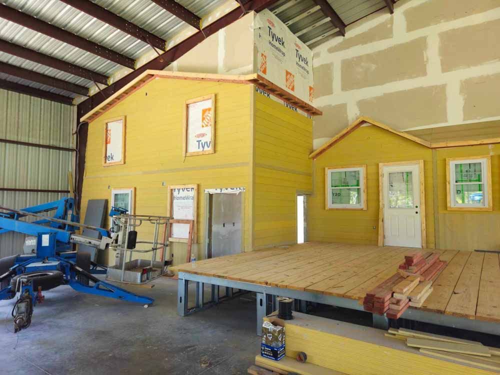 Yellow house model under construction inside a large building.