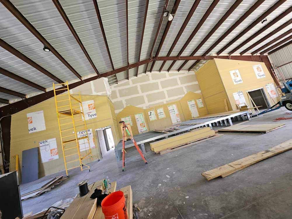 Interior of a building under construction, with exposed steel beams, unfinished walls, and construction equipment.