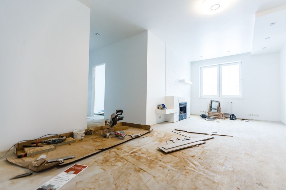 Interior room under construction with tools, debris, and bare floors.