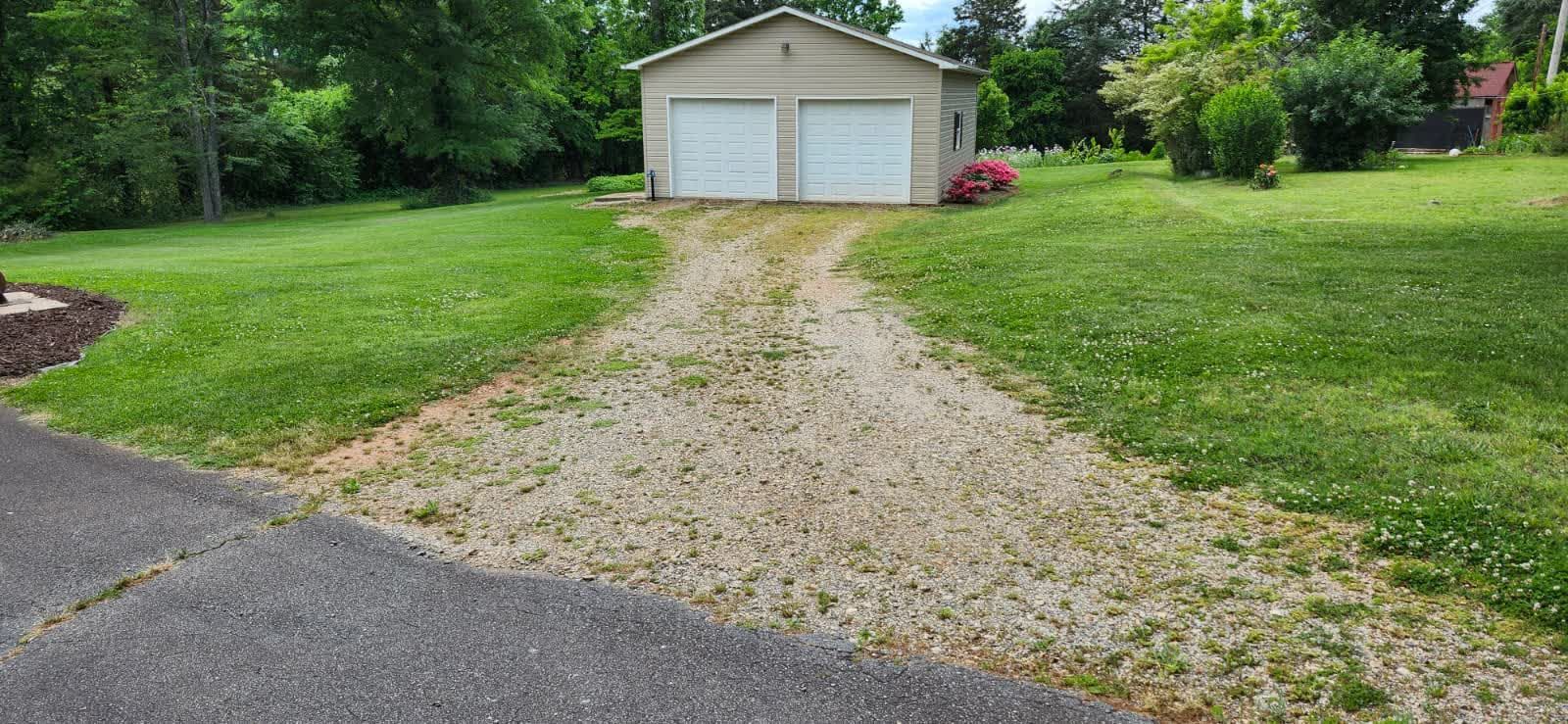 Gravel driveway leading to a garage with two doors; green grass on either side.