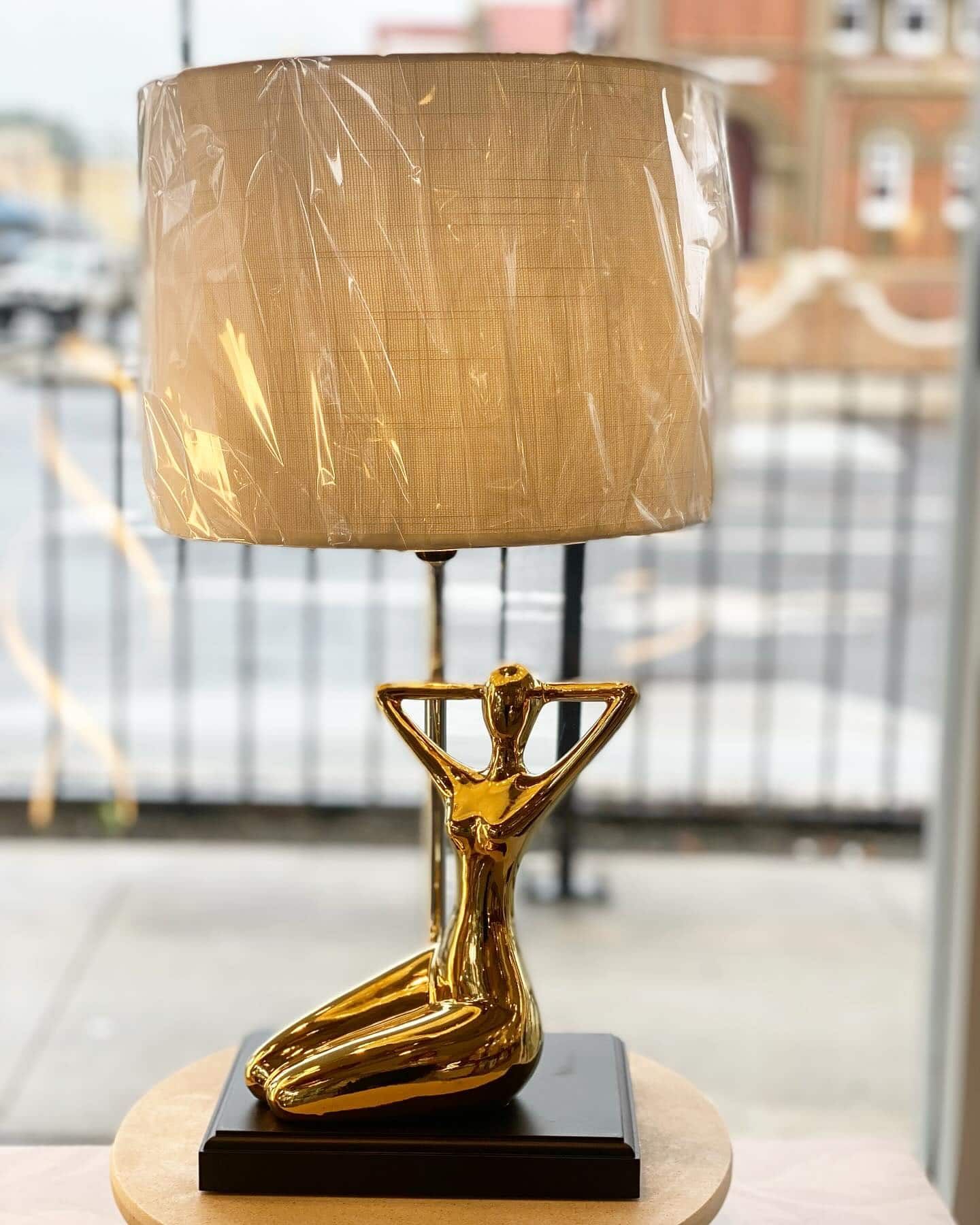 A Gold Lamp With a White Shade is Sitting on a Table — Brightway Lighting in Lismore, NSW