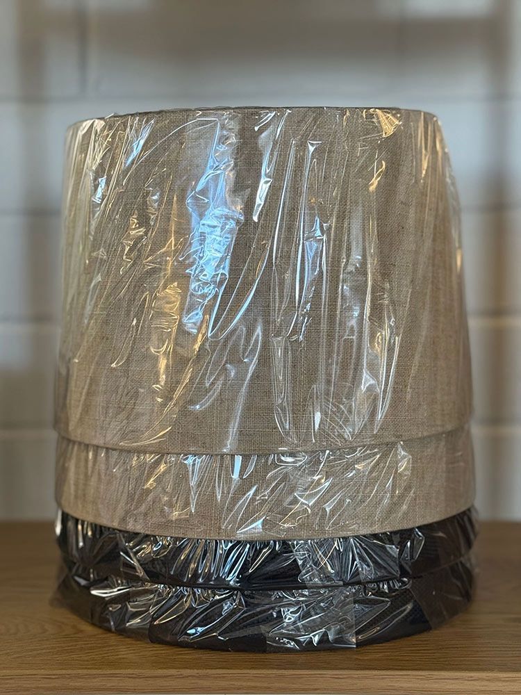 Stack Of Lamp Shades Wrapped In Plastic, Beige And Black Colors — Brightway Lighting in Lismore, NSW