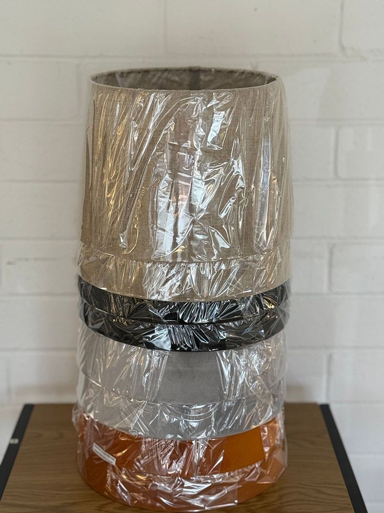 Stack Of Cylindrical Lampshades In Various Colors Wrapped In Plastic — Brightway Lighting in Lismore, NSW