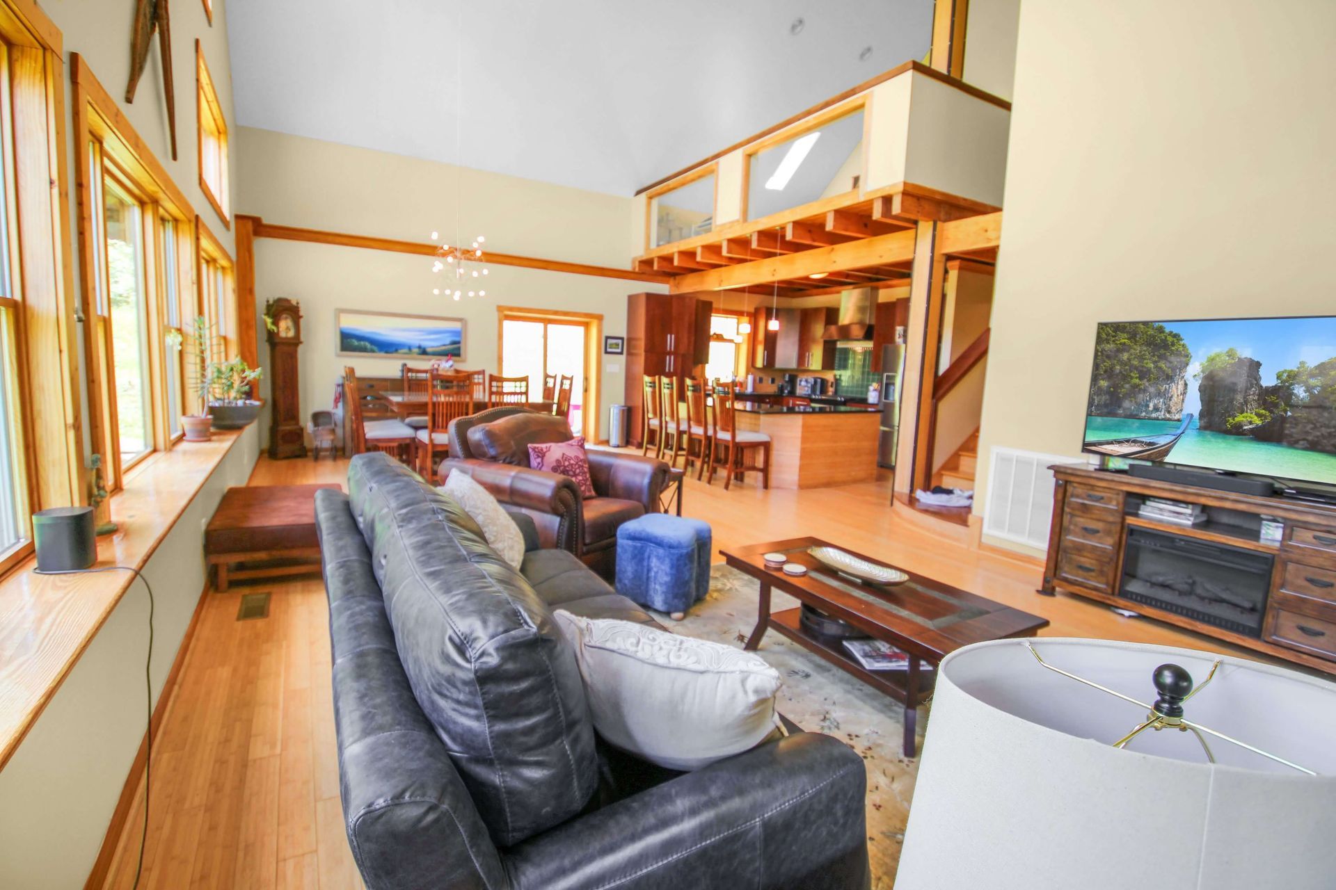 Spacious living area with a leather couch, dining area, and kitchen visible. High ceilings and a loft.