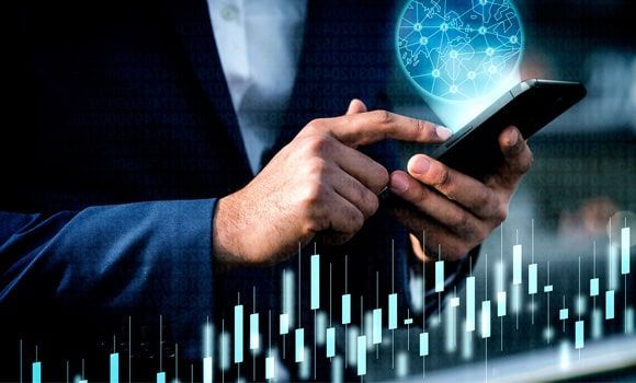 Un hombre con traje sostiene un teléfono celular en sus manos.