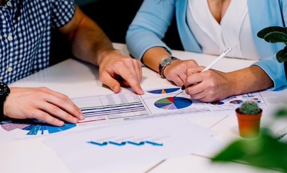 Un hombre y una mujer están sentados en una mesa mirando gráficos.