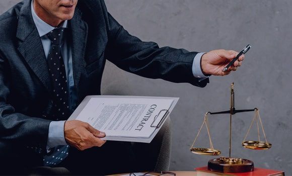 Un hombre con traje y corbata está sentado en una mesa sosteniendo un portapapeles y un bolígrafo.