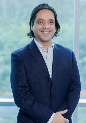Un hombre con traje y camisa blanca está parado frente a una ventana.