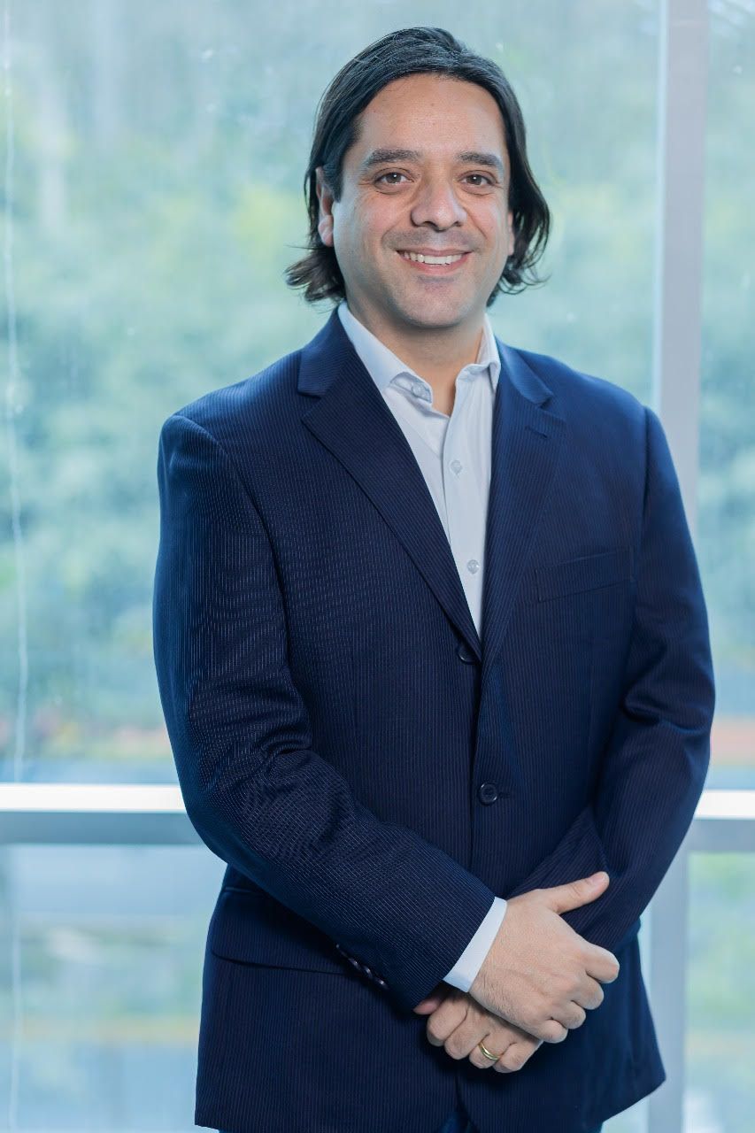 Un hombre con traje azul y camisa blanca está parado frente a una ventana.