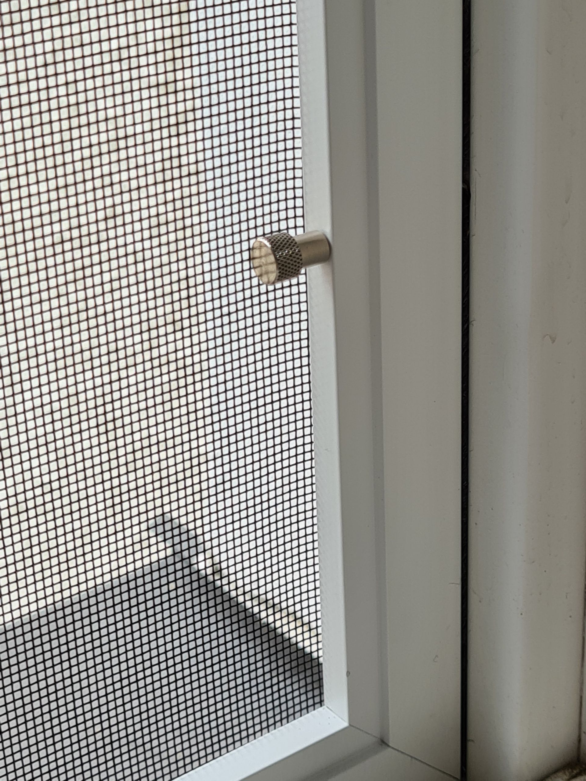 Eine Nahaufnahme einer Fliegengittertür an einem Fenster.