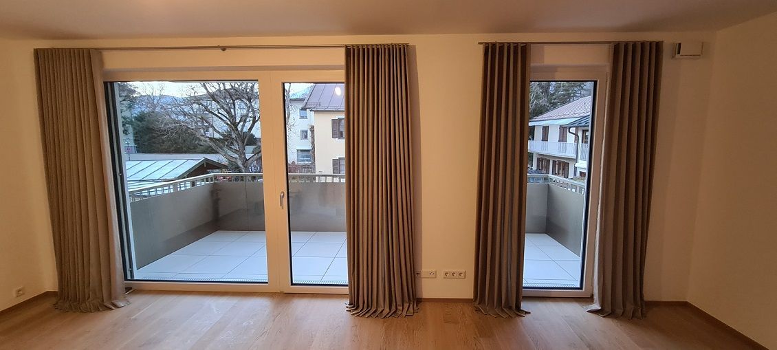 Ein leerer Raum mit Balkon und Glasschiebetüren.