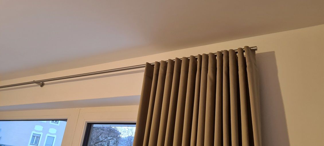 Eine Nahaufnahme eines Fensters mit Vorhängen, die von der Decke hängen.