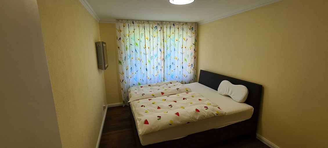 Ein Schlafzimmer mit einem Bett und einem Fenster mit Vorhängen.