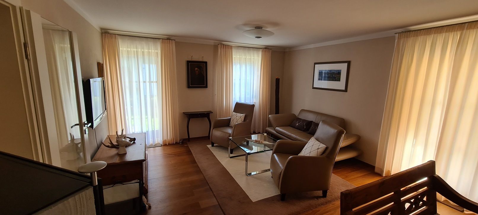 Ein Wohnzimmer mit einer Couch, Stühlen, einem Tisch und einem Fernseher.