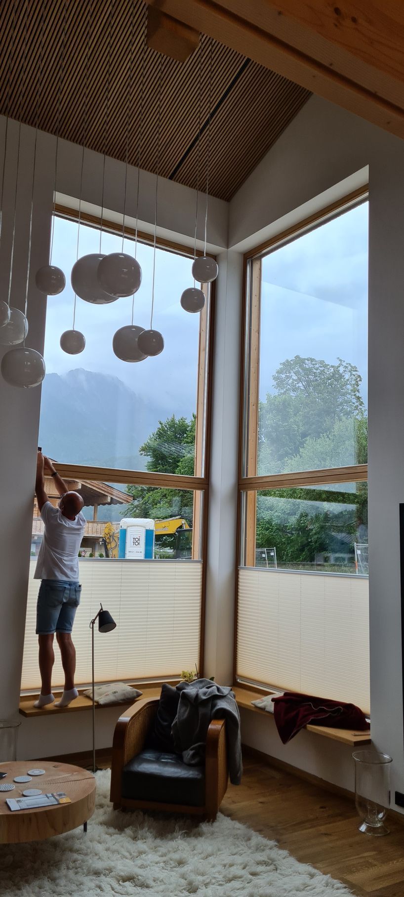 Ein Mann steht vor einem großen Fenster in einem Wohnzimmer.