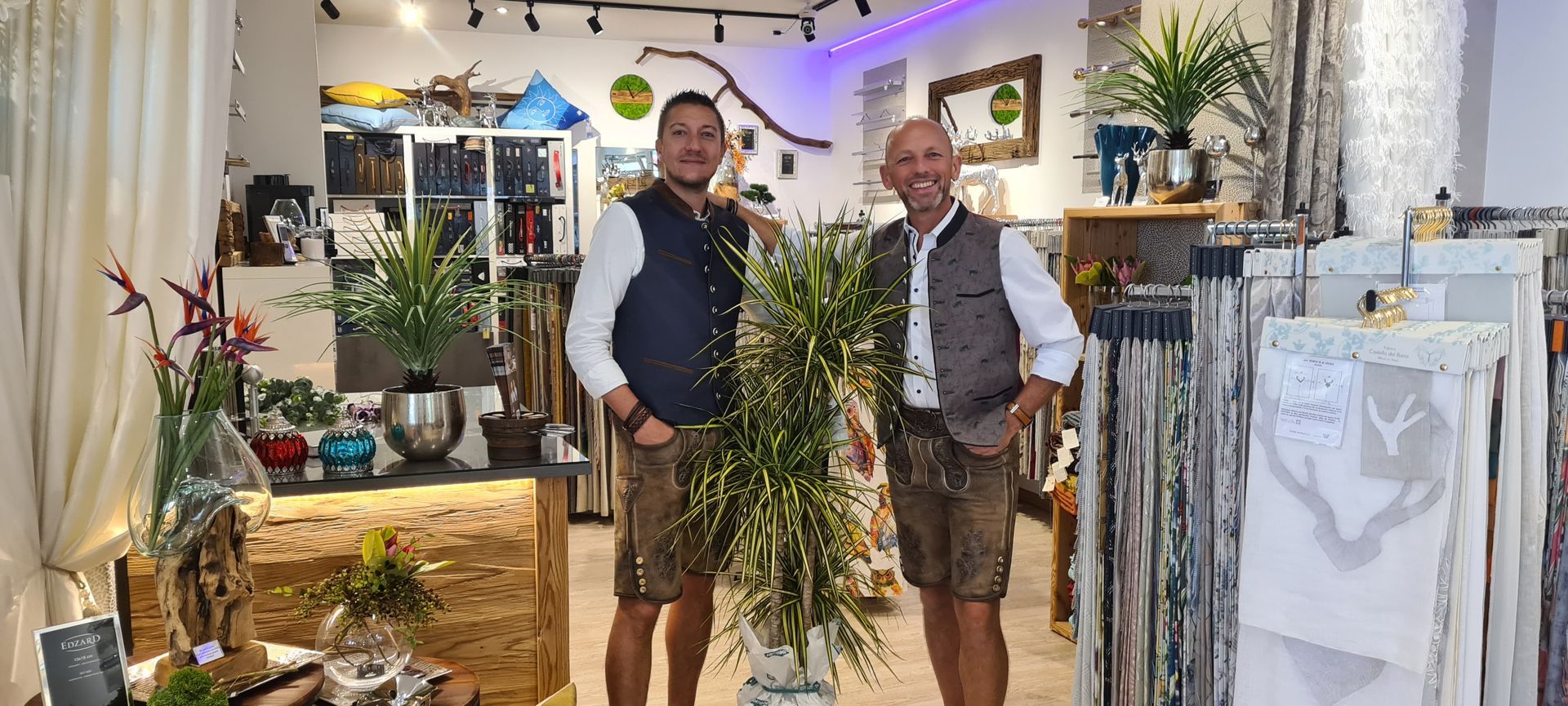 Zwei Männer stehen nebeneinander in einem Raum mit einer Vase mit Blumen.